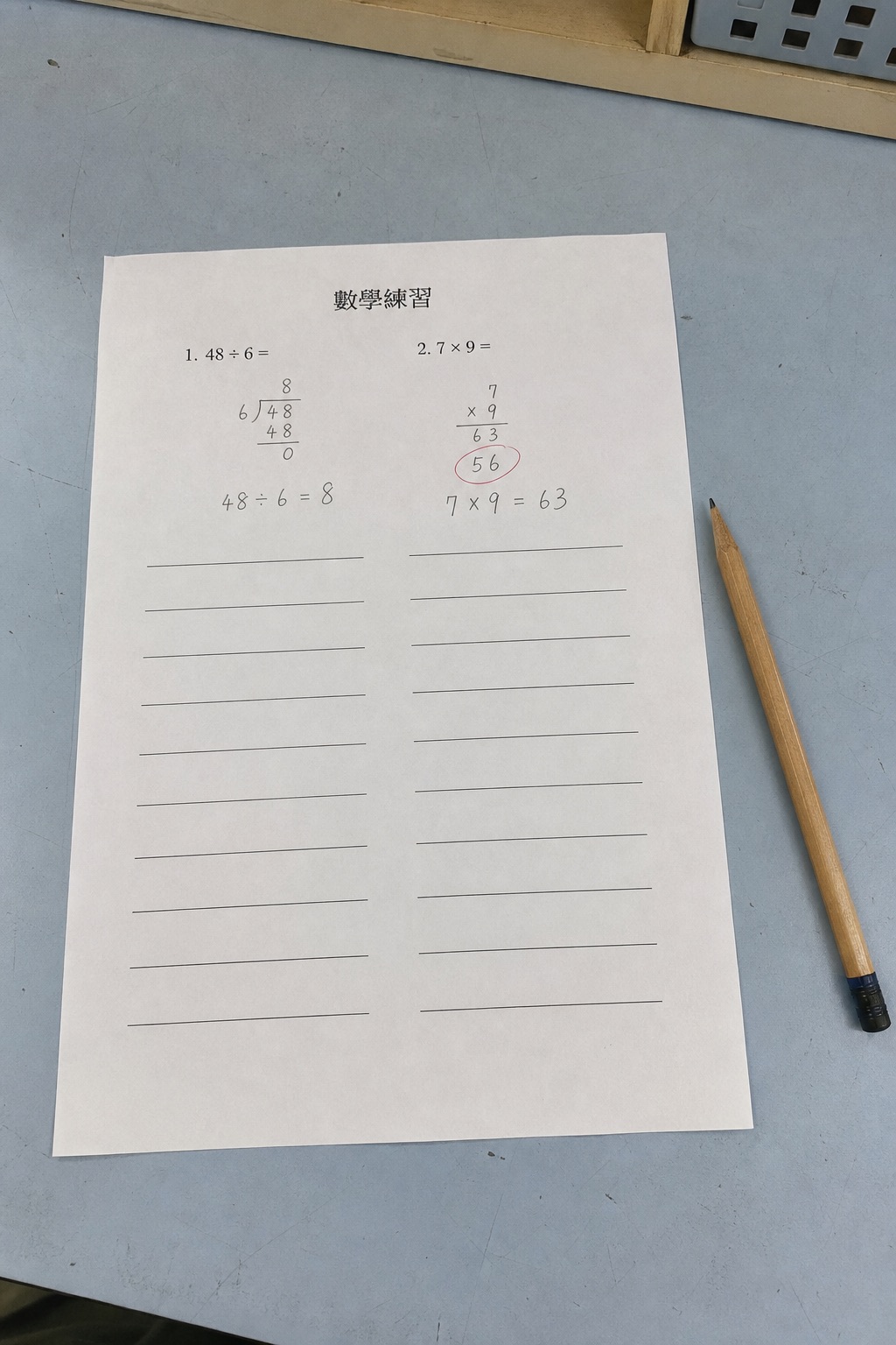 藍灰桌面上一張完整拍攝並有少量鉛筆作答和批改痕跡的數學練習紙
